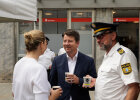 Kirchner am Stand im Austausch mit Polizist und Polizistin mit Kaffeebechern in der Hand