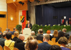 Innenminister Joachim Herrmann hinter Rednerpult vor Bühne zum Publikum