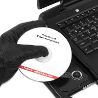 Das Foto zeigt ein Notebook mit geöffnetem CD-/DVD-Laufwerk; eine Hand in einem schwarzen Lederhandschuh entnimmt daraus eine CD/DVD mit der Aufschrift „Patente und Entwicklungsdaten – STRENG VERTRAULICH"
